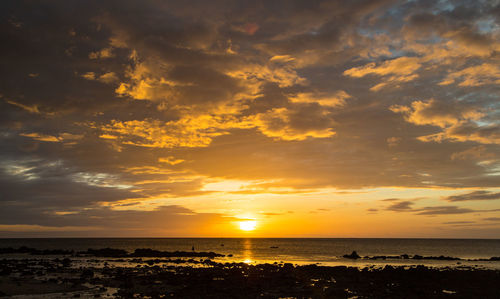 Scenic view of sea against dramatic sky during sunset