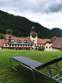 Building on land by mountains against sky