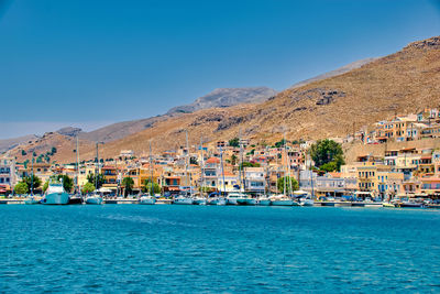 Buildings by sea against clear blue sky