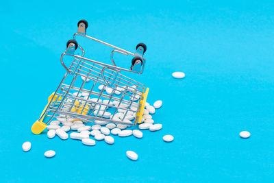 Close-up of shopping cart against blue background
