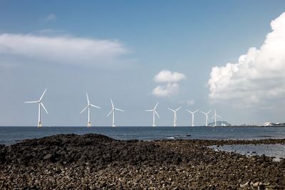 Wind turbines on beach against sky