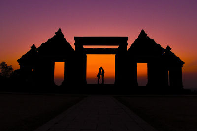 Silhouette couple kissing on gateway of ratu boko ruins against clear sky