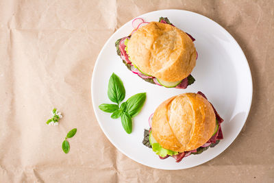 Ready-to-eat hamburgers with pastrami, vegetables and basil on a plate on craft paper