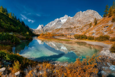 Colors of autumn season into the wild val veny with lake in foreground, aosta valley, italy