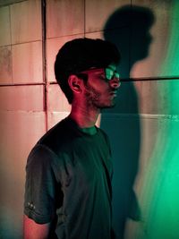 Side view of young man looking away against wall