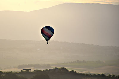 Hot air balloon flying over mountain against sky