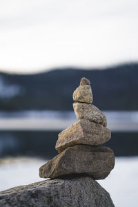 Close-up of stone stack on rock at beach against sky