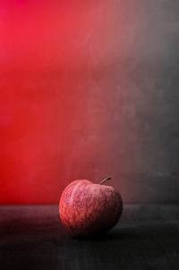Close-up of apple on table against red background