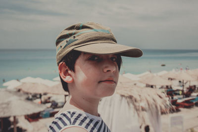 Close-up portrait of boy at beach against sky