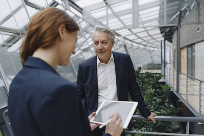 Smiling businessman and businesswoman with tablet in modern office building