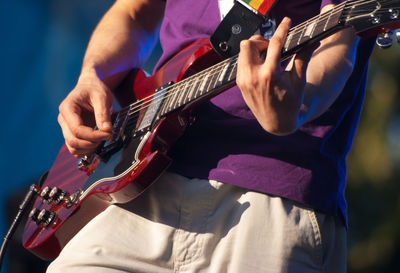 Midsection of man playing guitar at concert