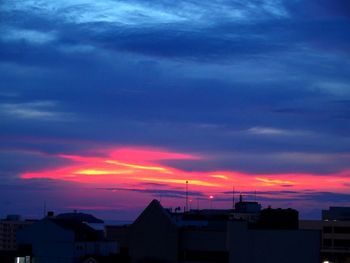 Silhouette houses against sky during sunset