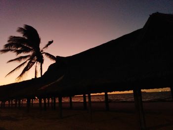 Silhouette palm trees on beach against clear sky at sunset