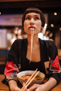 Portrait of young woman holding ice cream in restaurant