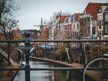 River by buildings in utrecht with windmill in background