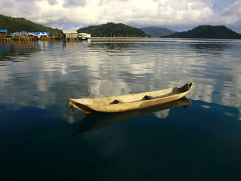 Boat moored on lake against sky