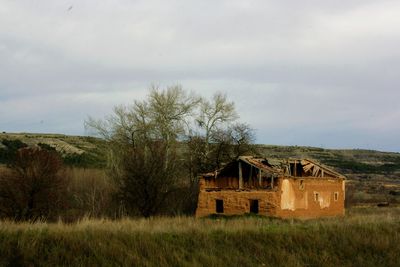 Abandoned house on field against sky