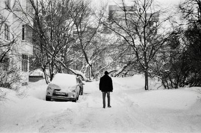 Rear view of man walking on snow covered road