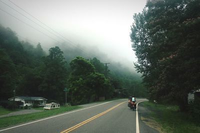 People riding bicycles on road during foggy weather