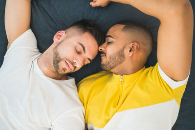 High angle view of gay men lying on bed