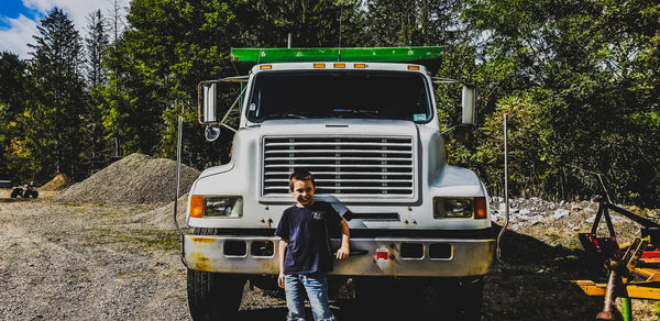 Portrait of smiling boy standing against truck