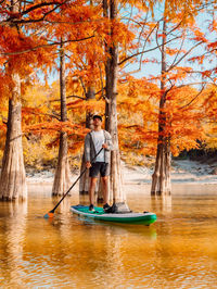 Rear view of woman kayaking in lake during autumn