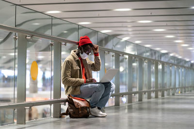 Man wearing mask using laptop at airport