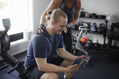 Man and woman looking at digital tablet in gym