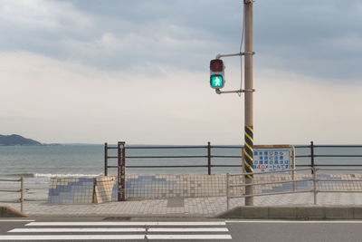 Road sign by sea against sky