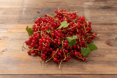 Red currants with leaves on a wooden table on background. harvest of ripe summer berries. closeup.