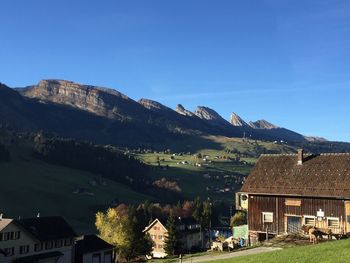 Houses by mountains against clear blue sky