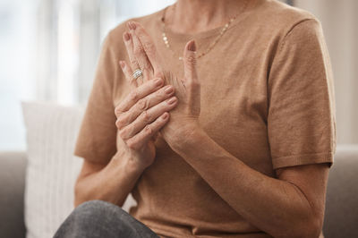 Midsection of woman sitting on sofa at home