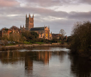 Cathedral at waterfront against cloudy sky