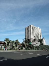 Street by modern buildings against sky