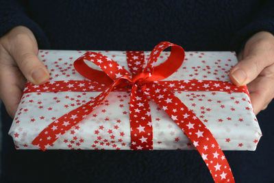 Midsection of woman holding wrapped christmas present with red ribbon