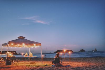 Man at beach against sky during sunset