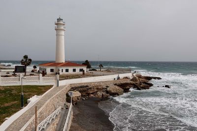 Lighthouse by sea against sky