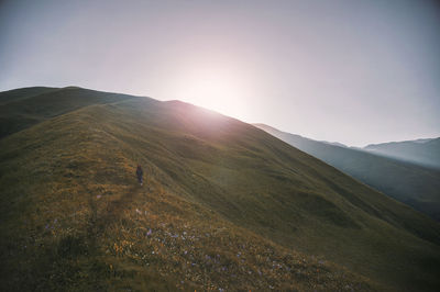 Mid distance view of young woman standing on mountain against clear sky