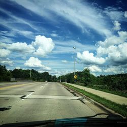 Road passing through landscape against cloudy sky