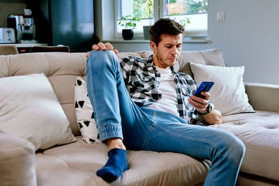 Man using smartphone while resting on sofa. online social media