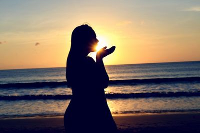 Silhouette man standing on beach against sky during sunset