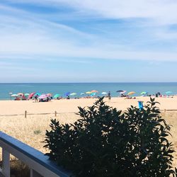 People at beach against sky during summer