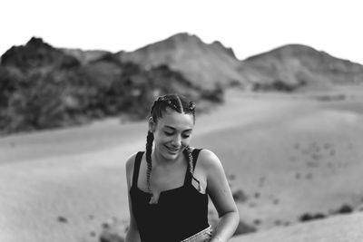 Smiling young woman at beach against sky