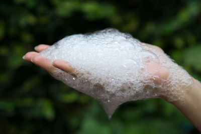 Close-up of hand holding soap sud