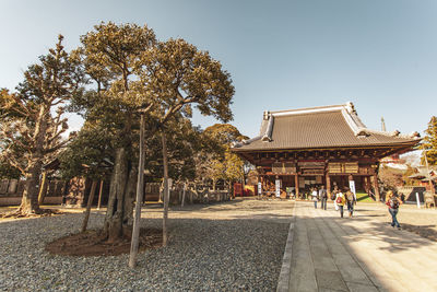 People outside temple against clear sky