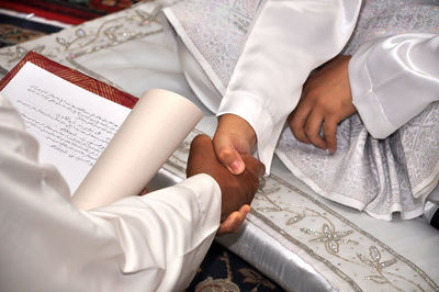 Cropped image of bridegroom and man holding hands during wedding ceremony