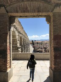 Rear view of woman standing by historic building against sky