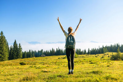 Rear view of woman standing on field against clear sky