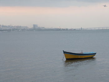 Boat moored in sea against sky during sunset