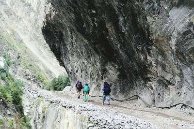Rear view of people on walkway by rock formation